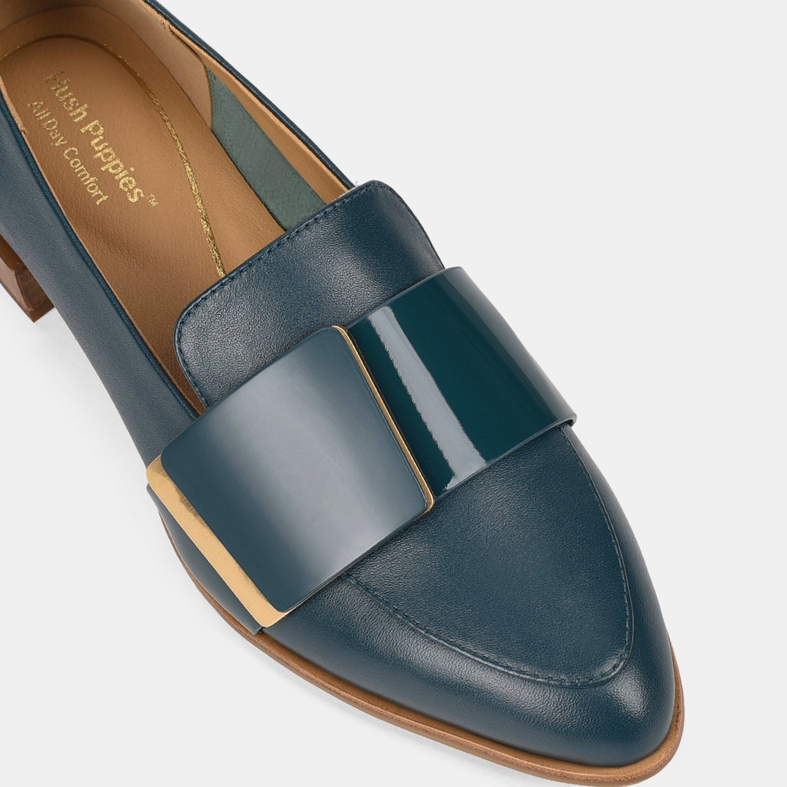 Navy loafer shoe with a brown sole on a light gray background