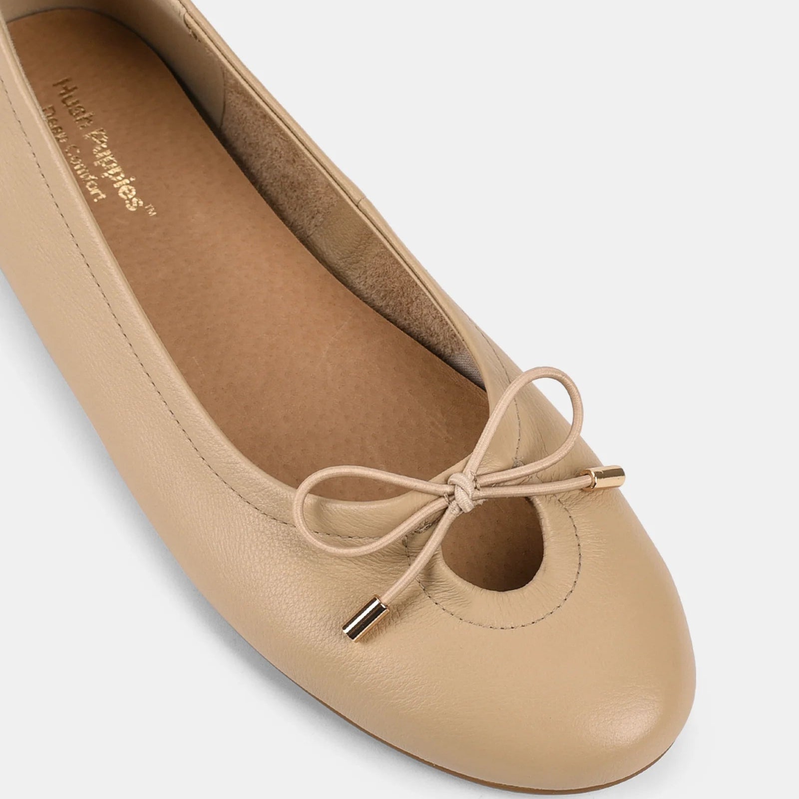 Beige flat shoe with a bow on a white background