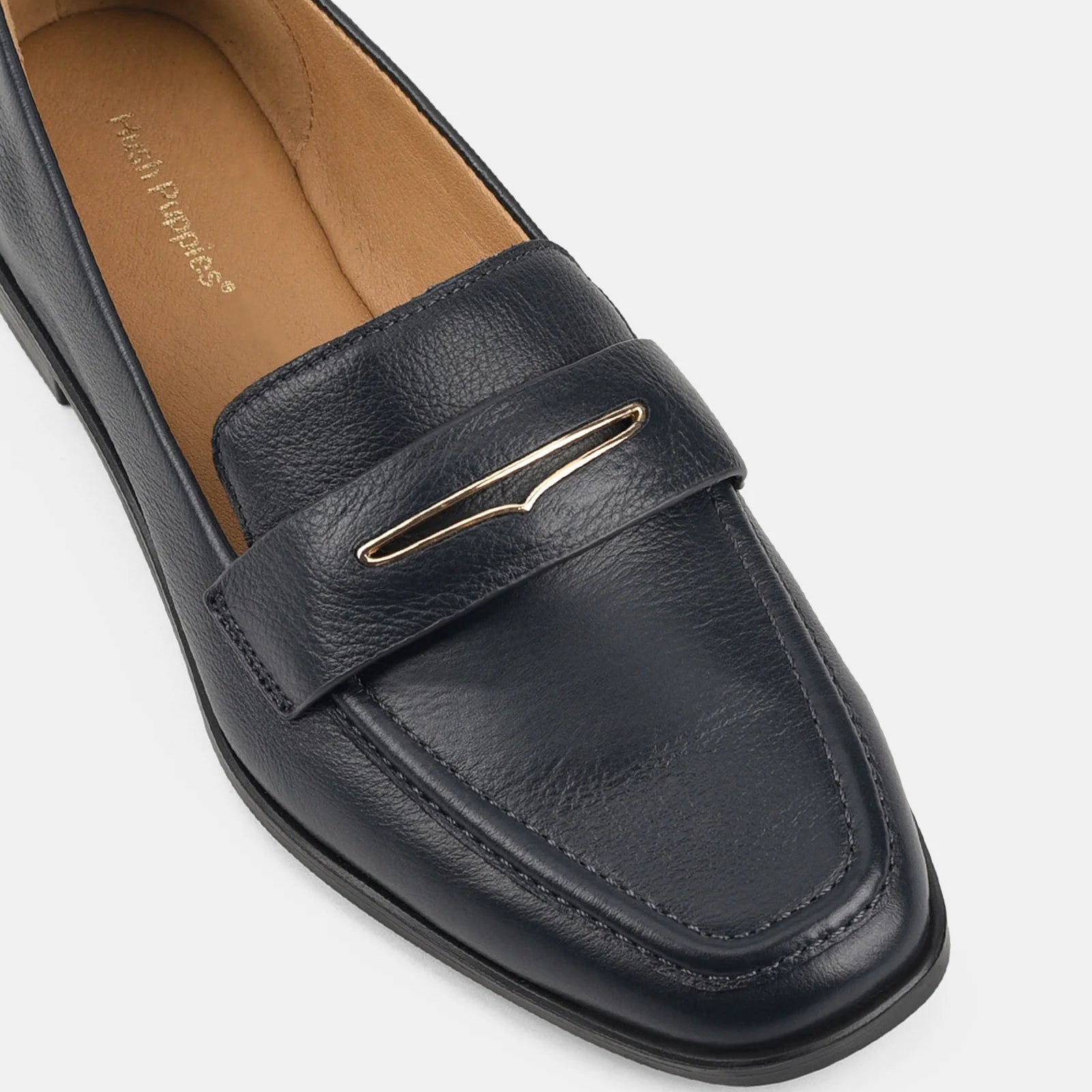 Black loafer shoe with gold buckle on a white background
