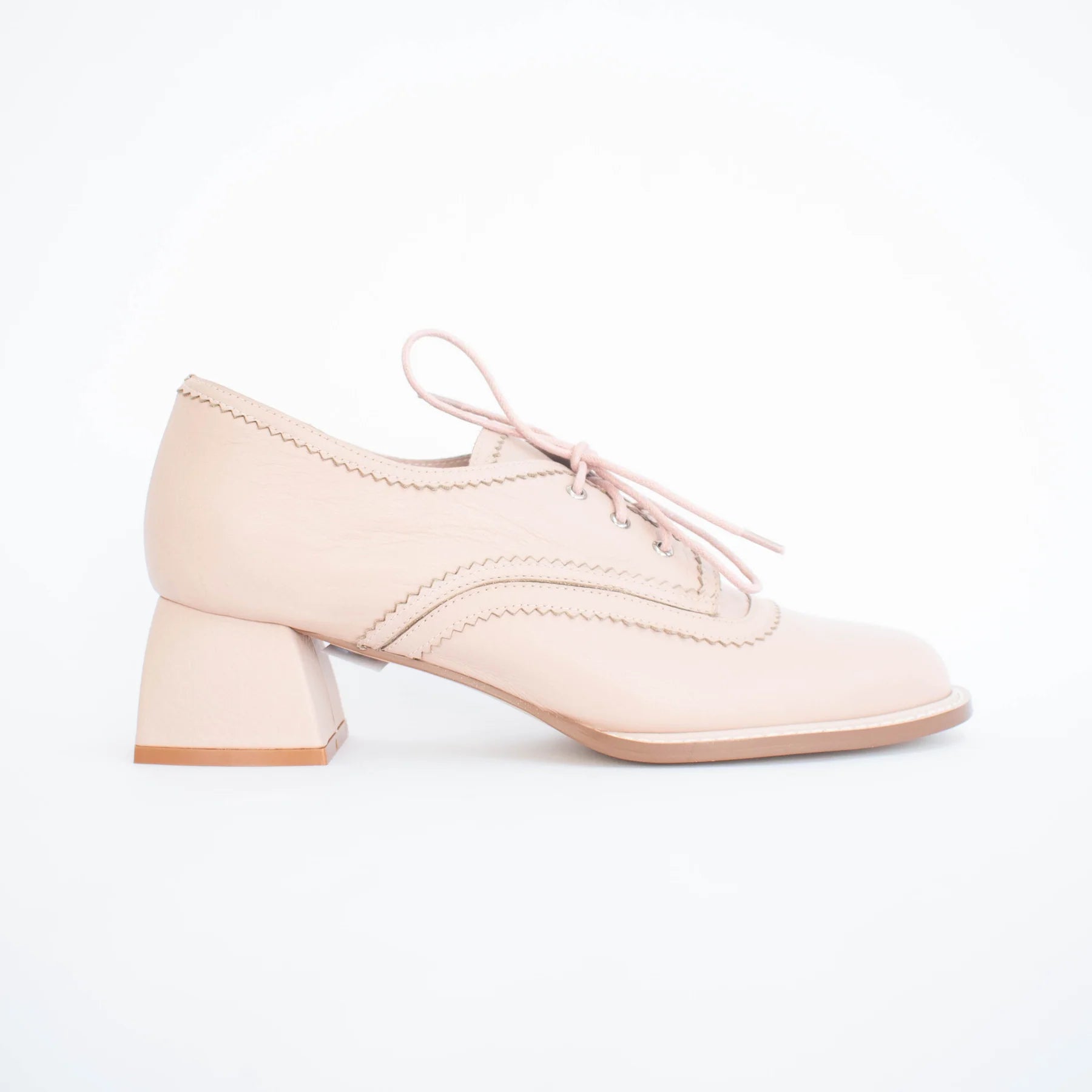 Pink leather brogue shoe on a white background
