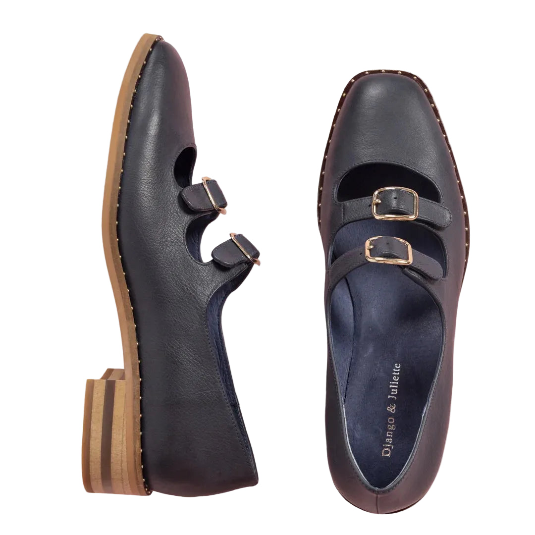 Pair of black shoes with gold buckles on a pink background