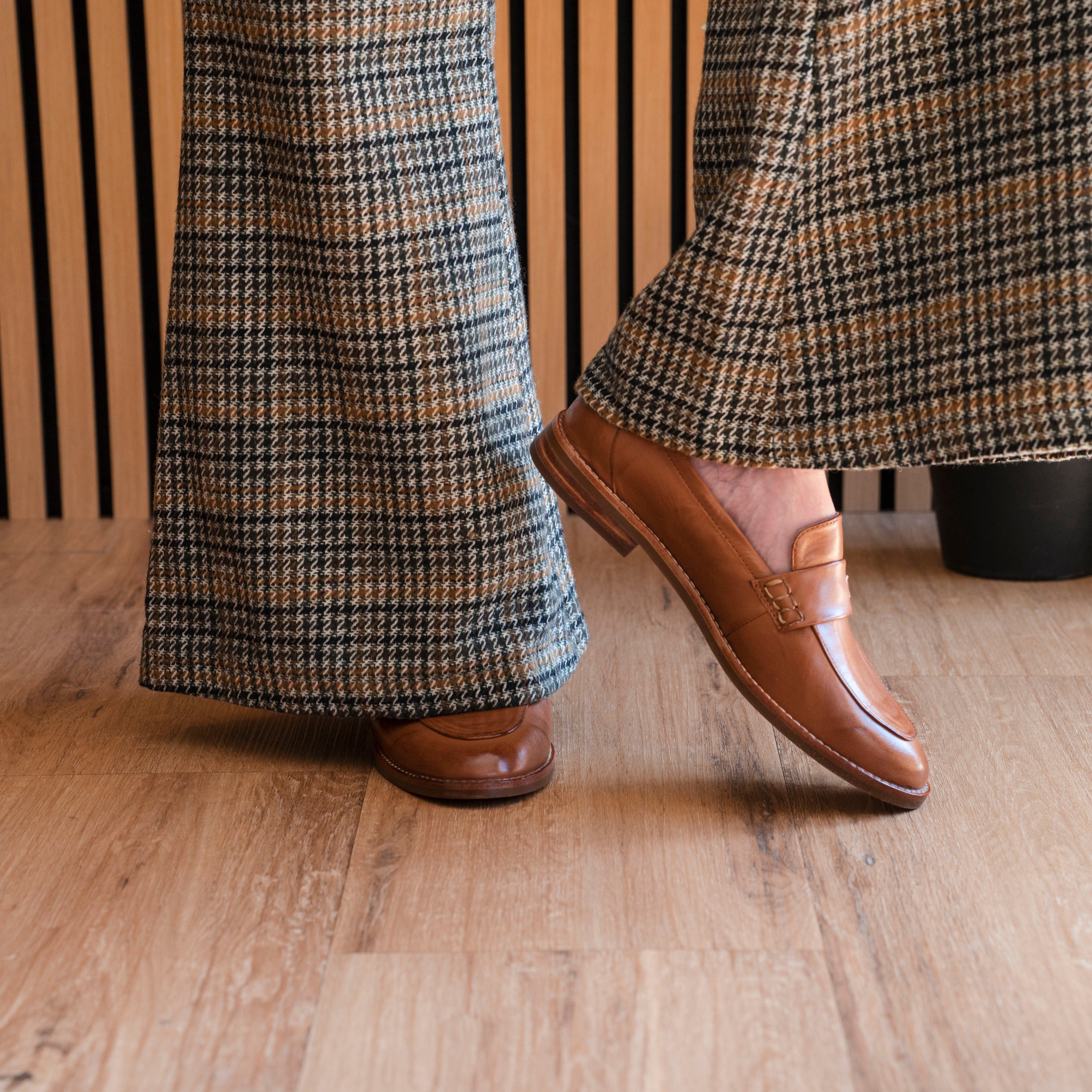 Brown leather shoes and plaid pants on a wooden floor