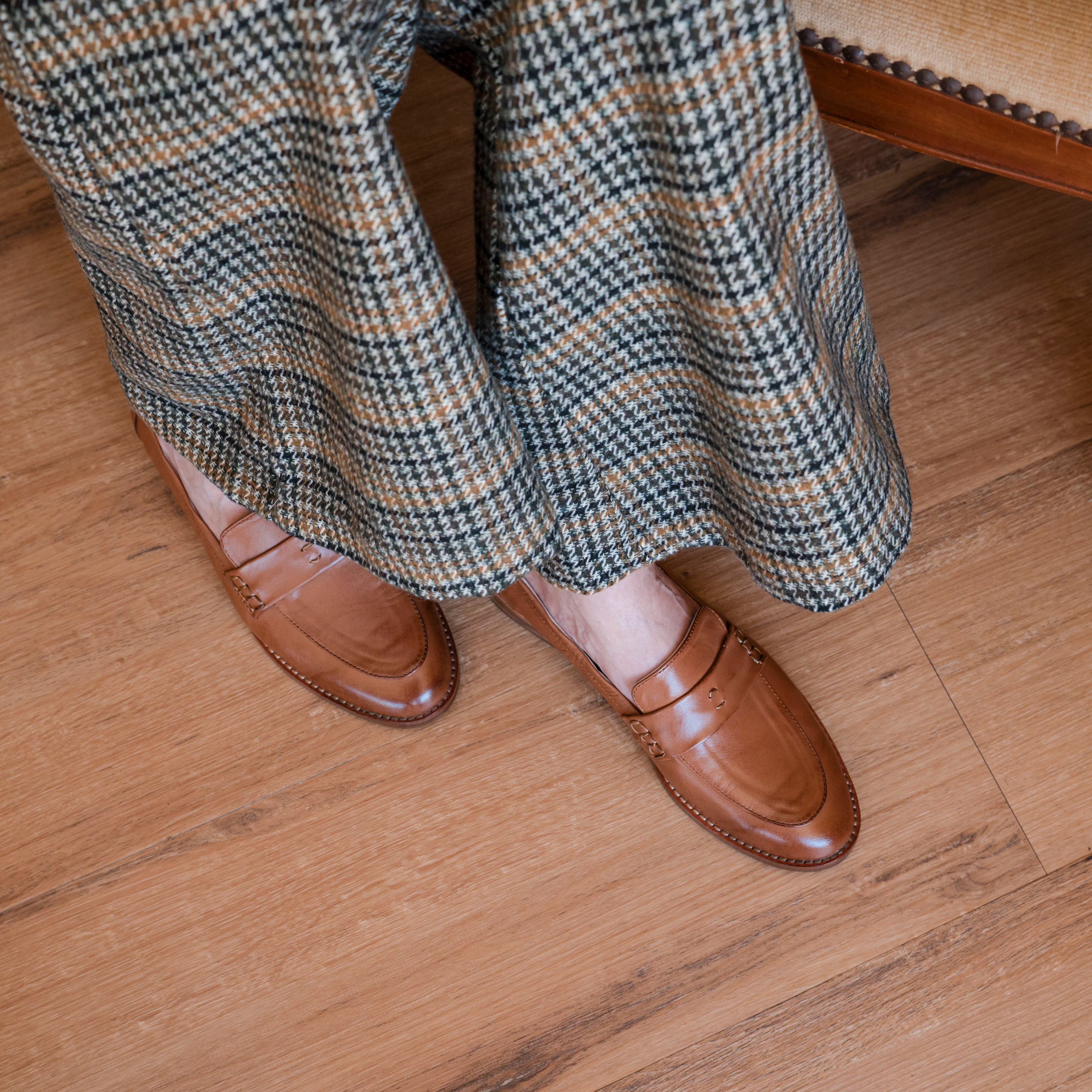 Brown loafers and plaid pants on a wooden floor