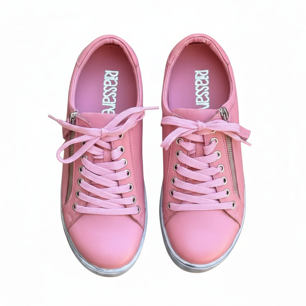 Pair of pink sneakers with zippers on a wooden surface