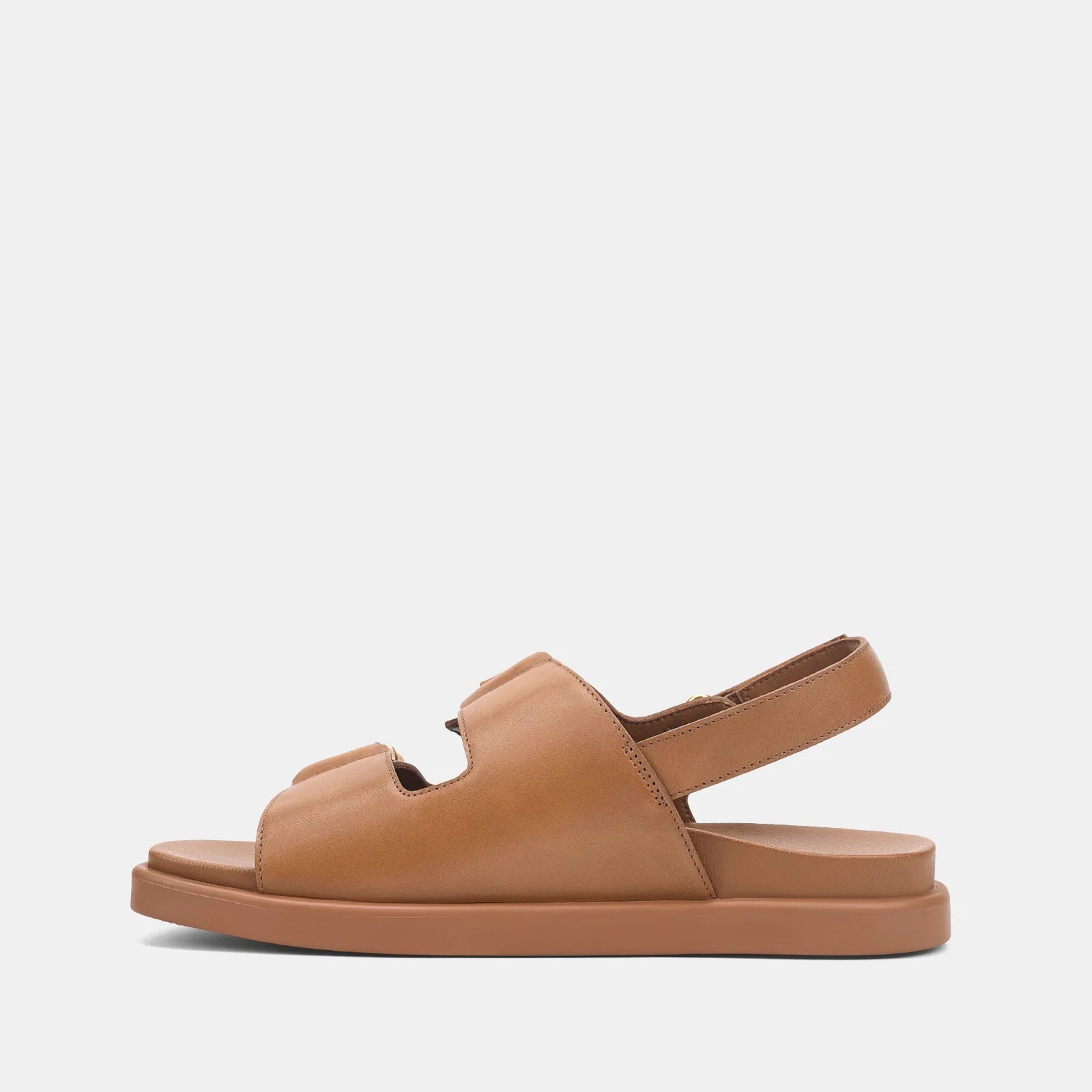 A single tan leather flat sandal with double straps and an ankle strap, shown in a side profile on a light gray background.