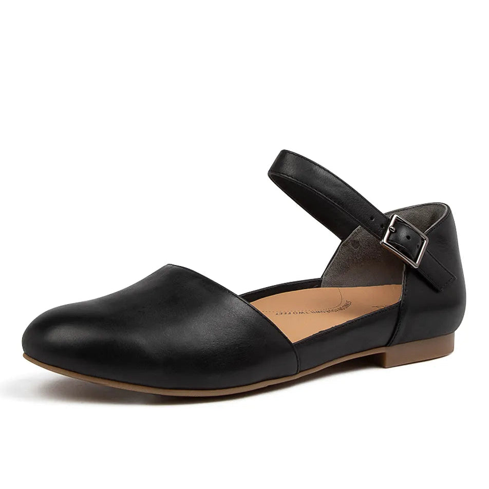 Black leather flat shoe with a strap and buckle on a white background